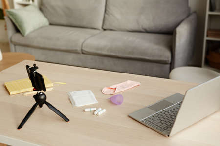 Background image of various feminine hygiene products on table with smartphone camera set for video...