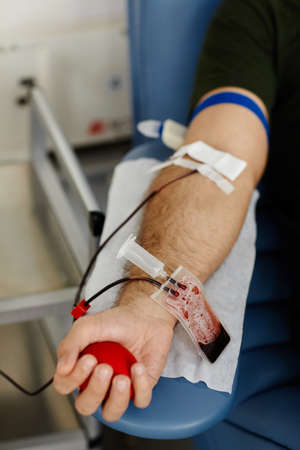 Closeup of male hand squeezing stress ball while giving blood at donation centerの写真素材