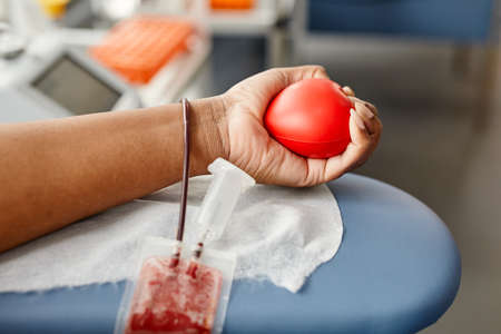 Closeup of unrecognizable young woman donating blood and holding red squeeze ball, copy spaceの写真素材