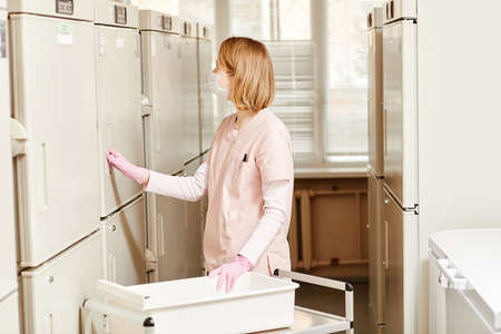 Side view portrait of female nurse in storage room at blood donation clinic, copy spaceの写真素材