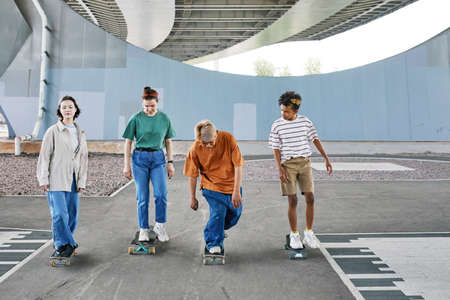 Full length shot of diverse group of teenagers riding skateboards in urban skating area, copy spaceの写真素材