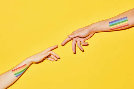 Vibrant shot of two hands reaching out with  flags on yellow background Creation styleの写真素材
