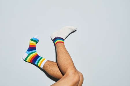 Minimal shot of playful man wearing mismatched socks with rainbow symbols feet up, copy spaceの写真素材