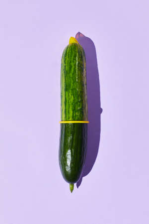 Minimal shot of single cucumber with condom on pastel background safe sex and protection conceptの写真素材