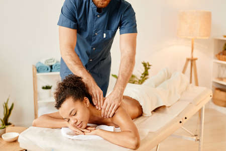 Portrait of young African American woman enjoying back massage in SPA and smiling blissfullyの写真素材