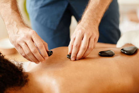 Close up of young woman enjoying hot stone therapy in SPA session, copy spaceの写真素材