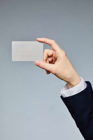 Close up of female hand holding business card mockup to camera against grey background