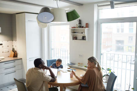 Wide angle scene on multiethnic family at dinner table in kitchen, copy space