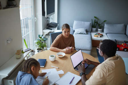 High angle home scene of modern multiracial family at dinner table in kitchen, copy space