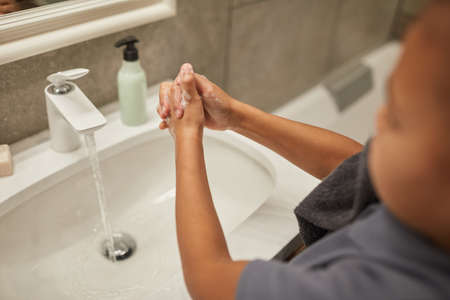Close up of little black girl washing hands in bathroom sink, night or morning hygiene, copy spaceの写真素材