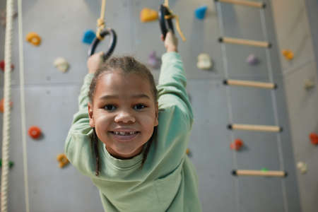 Portrait of active black child hanging on sports rings at home and smiling at camera, copy spaceの写真素材