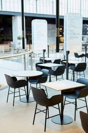 Minimal background image of minimal food court interior in black and white with tables and chairs in row, copy spaceの写真素材