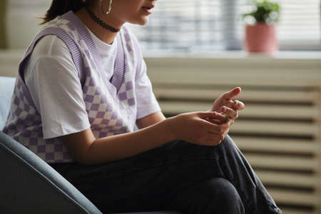 Close-up of teenage girl sitting on armchair and talking during psychotherapy sessionの写真素材