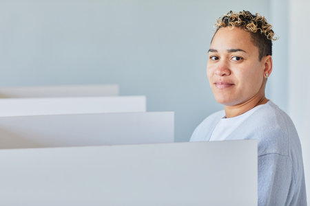 Minimal portrait of young black woman voting on election day and looking at camera, copy space