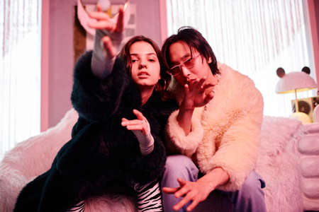 Portrait of young couple clubbing and looking at camera in pink neon light