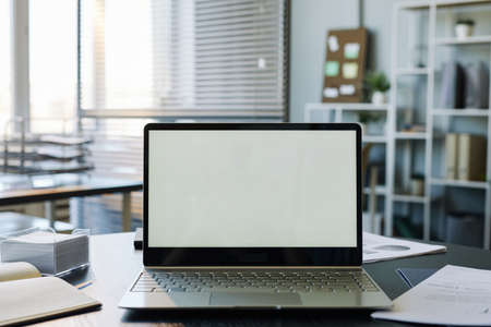 Background image of mock up computer with blank white screen in empty office interior, copy space
