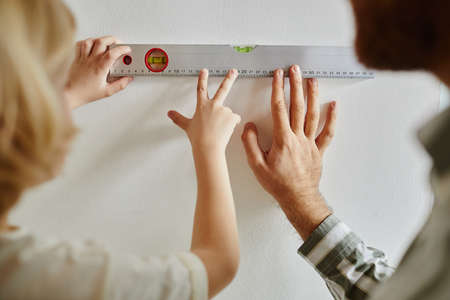 Close up of father and son using level measure while doing DIY home improvement projectの写真素材