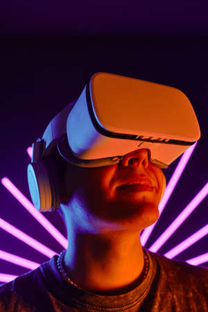 Futuristic portrait of smiling man wearing VR headset with neon light beams in background
