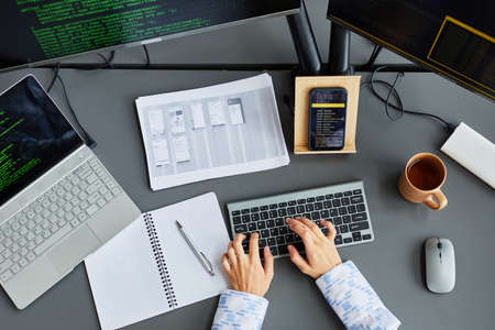 High angle view of female IT professional typing on keyboard at her workplace working with codes on...