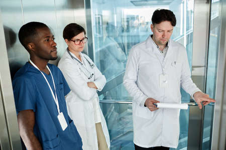 Diverse group of doctors in elevator at modern hospital building