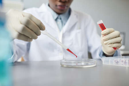 Close up of female technician preparing test sample while working in medical science lab, copy space
