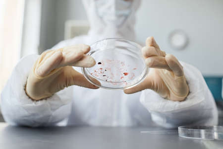 Close up of unrecognizable scientist wearing full protective gear while performing blood test in...