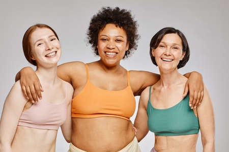 Minimal waist up diverse group of real women wearing underwear and laughing happily against grey backgroundの写真素材