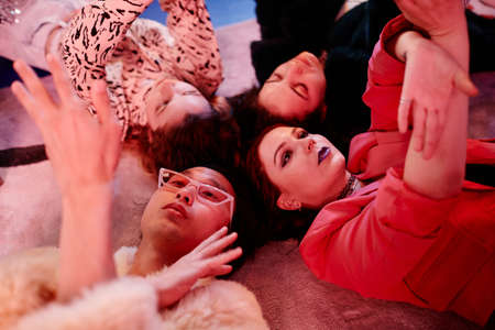 Close up of vogue dance crew lying on floor in red neon light and doing hand movementsの写真素材