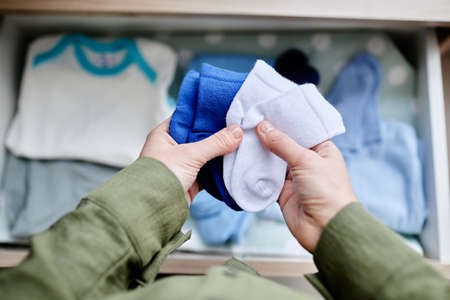 Closeup of pregnant young woman folding baby clothes while expecting child, copy spaceの写真素材