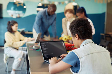 Back view of boy using laptop in engineering class and programming robots, copy spaceの写真素材