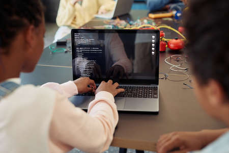 Back view of kids using laptop in engineering class and programming robots, copy spaceの写真素材