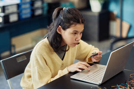 Portrait of young Asian girl using laptop in engineering class and programming robot, copy spaceの写真素材