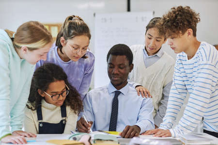 Portrait of young black teacher smiling with diverse group of children in schoolの写真素材