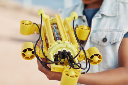 Close up of unrecognizable child holding yellow robot model, engineering for kids backgroundの写真素材