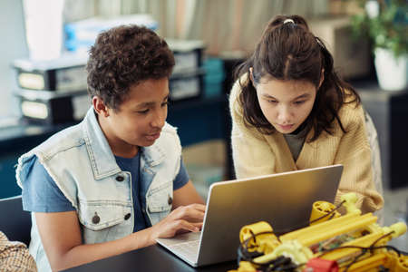 Portrait of boy and girl using laptop together and programming robots during engineering class at schoolの写真素材