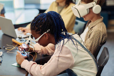 Side view portrait of black teenage girl connecting computer parts in engineering class, copy spaceの写真素材