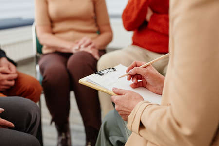 Close-up of psychologist making notes in document during psychotherapy session with peopleの写真素材