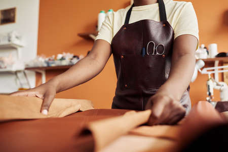 Close up of unrecognizable female artisan working with genuine leather in workshop, copy spaceの写真素材