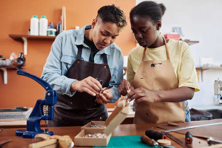 Waist up portrait of two female artisans in leatherworking shop creating handmade pieces togetherの写真素材