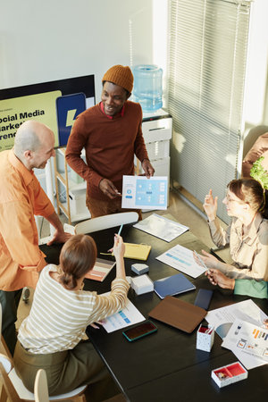High angle view at creative business team meeting in office, diverse group of people sitting at table and communicatingの写真素材