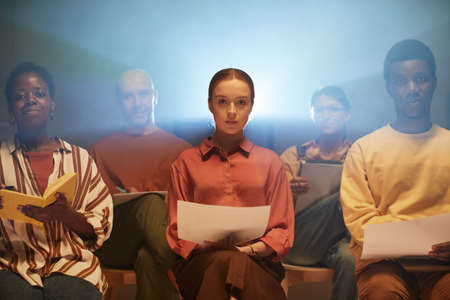 Moody shot of people backlit by projector rays whle sitting on chairs in audience at business seminarの写真素材