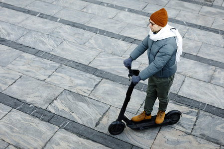 High angle view of guy in warm clothing riding on scooter in the cityの写真素材