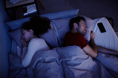 High angle view of young couple sleeping under blanket in bed at night
