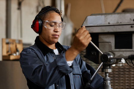 Portrait of female worker operating machine units in industrial workshop, copy space