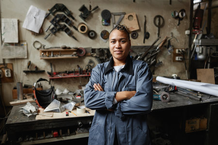 Waist up portrait of multiethnic female worker posing in workshop with arms crossed and looking at camera, copy spaceの写真素材
