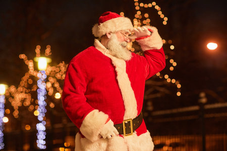Side view portrait of traditional Santa Claus looking around in night city settingの写真素材