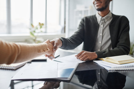Close up of young black man shaking hands with HR manager while greeting each other at job interviewの写真素材