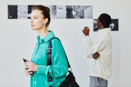 Minimal portrait of young woman in art gallery with pictures in background, copy spaceの写真素材
