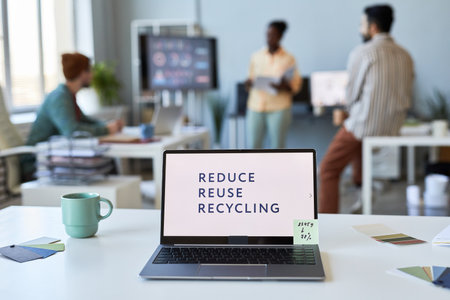 Laptop with slogan consisting of three words on white screen standing on table among mug and color...