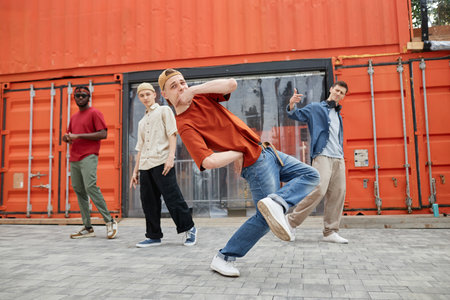 Full length shot of all male dance team performing hip-hop in urban city setting